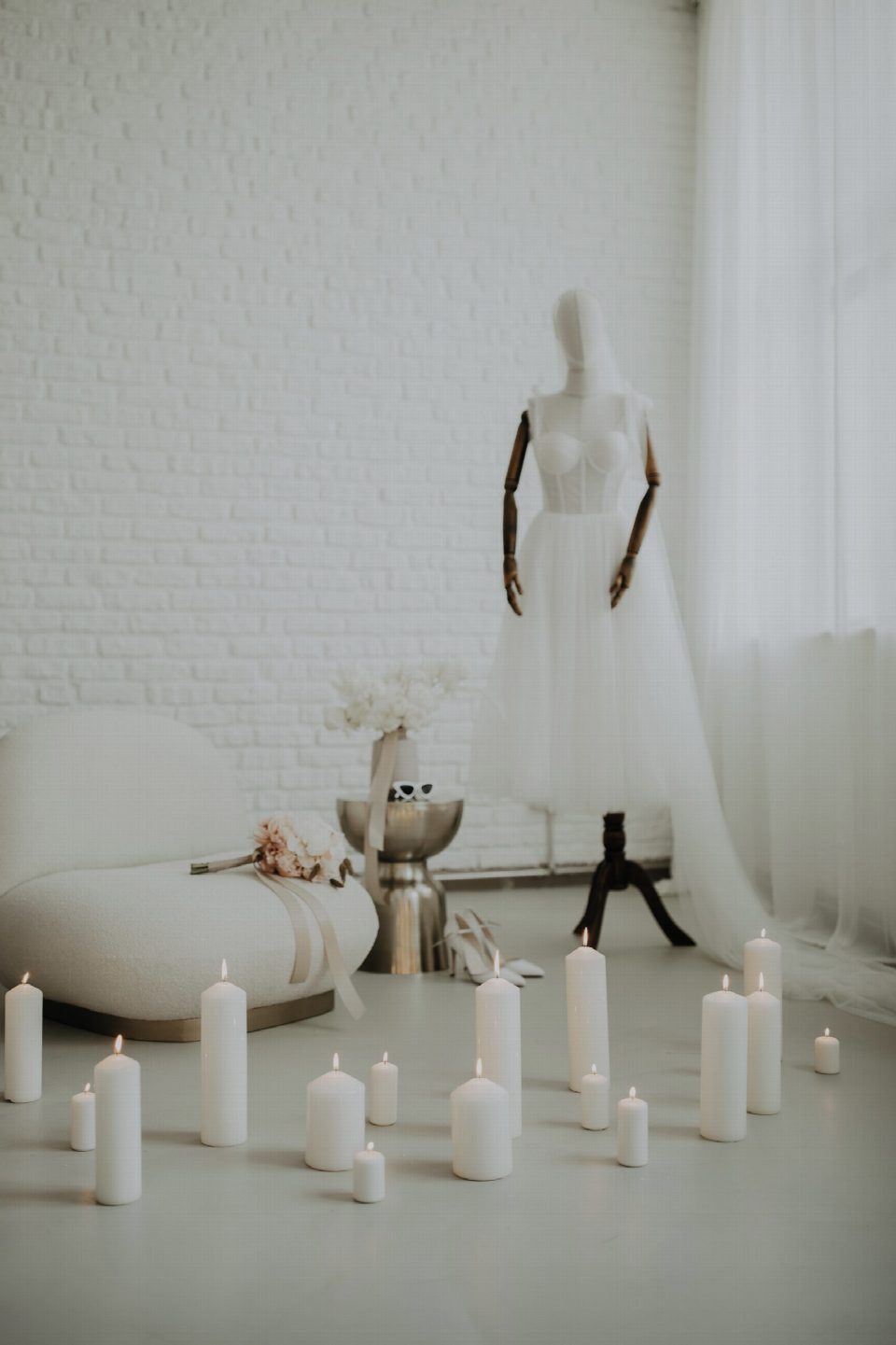 Brautkleid auf einer Büste zwischen Kerzen